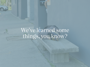 Image of a person sleeping on a concrete bench with the words "We've learned some things, you know?" in white letters.