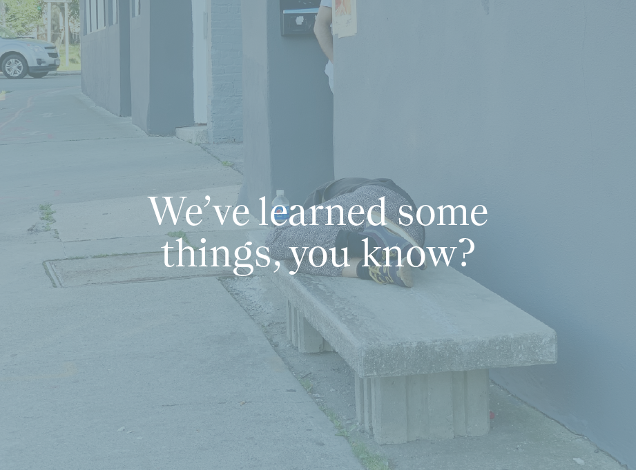 Image of a person sleeping on a concrete bench with the words "We've learned some things, you know?" in white letters.